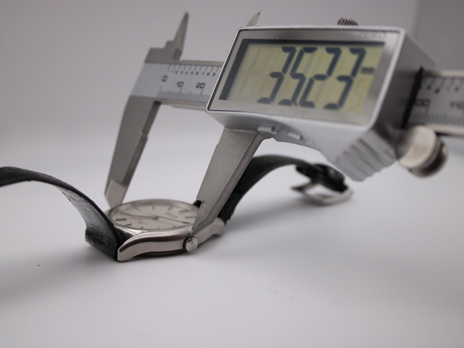 Digital caliper measuring the case diameter of the watch, showing a precise reading of 35.23 mm.