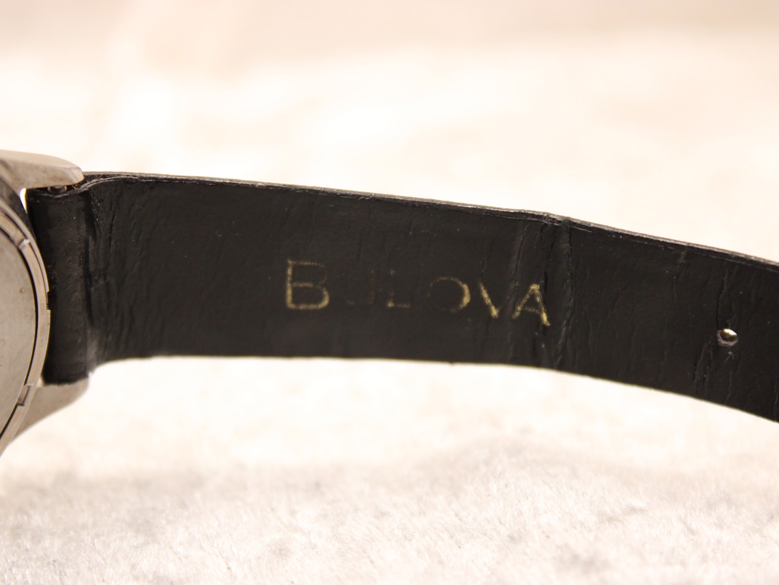 Close-up of the black leather strap, revealing the embossed 'Bulova' signature on its inner lining.