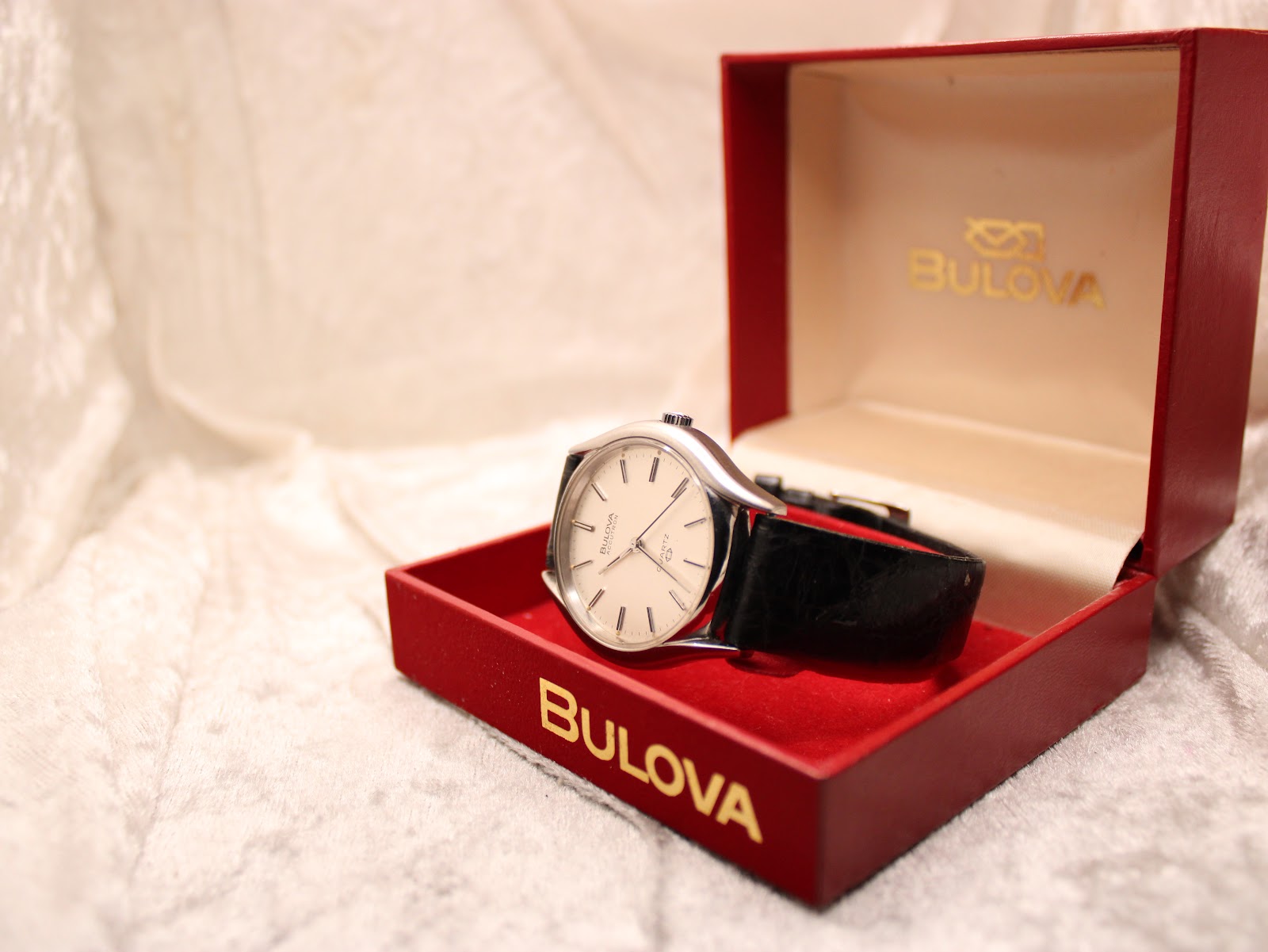 Bulova Accutron watch resting within its open original red presentation box with gold lettering.