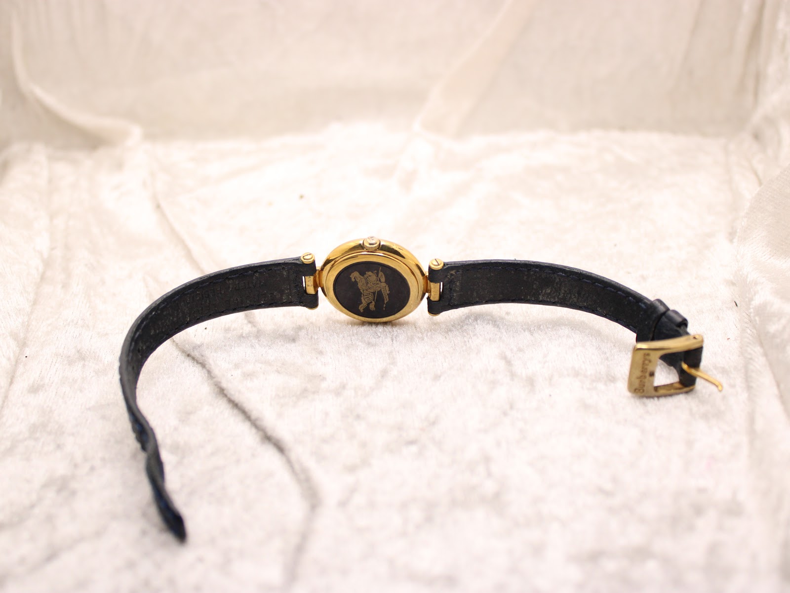 Back view of the Burberrys watch with unclasped blue leather strap, showing the case back logo.