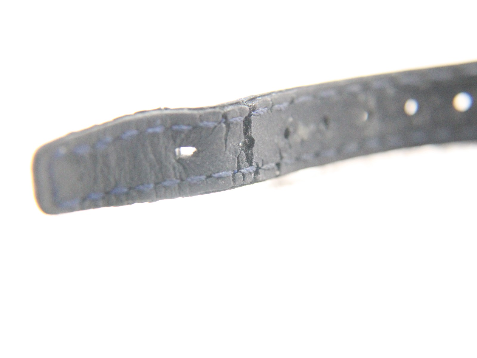 View of the end of the blue leather strap, showing wear near the buckle holes.