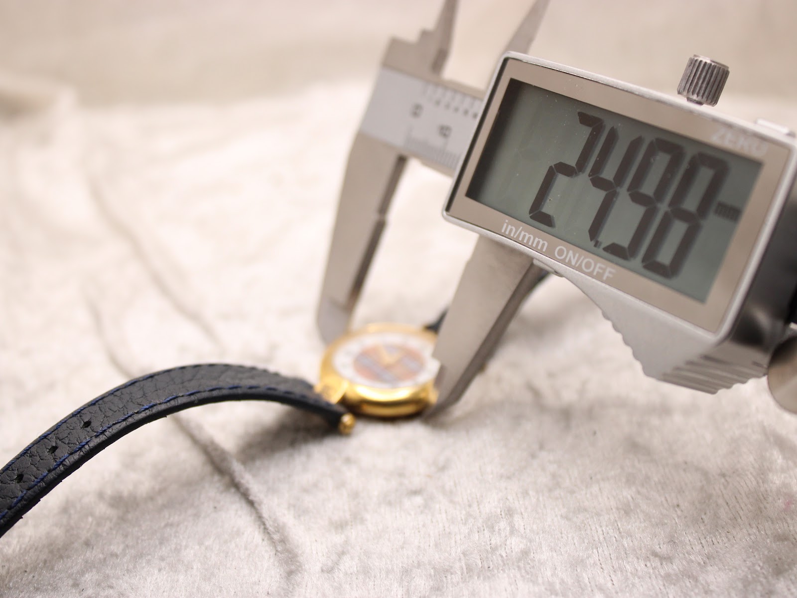 Digital caliper measuring the watch case diameter, showing 24.98mm.