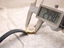 Digital caliper measuring the watch case diameter, showing 24.98mm.