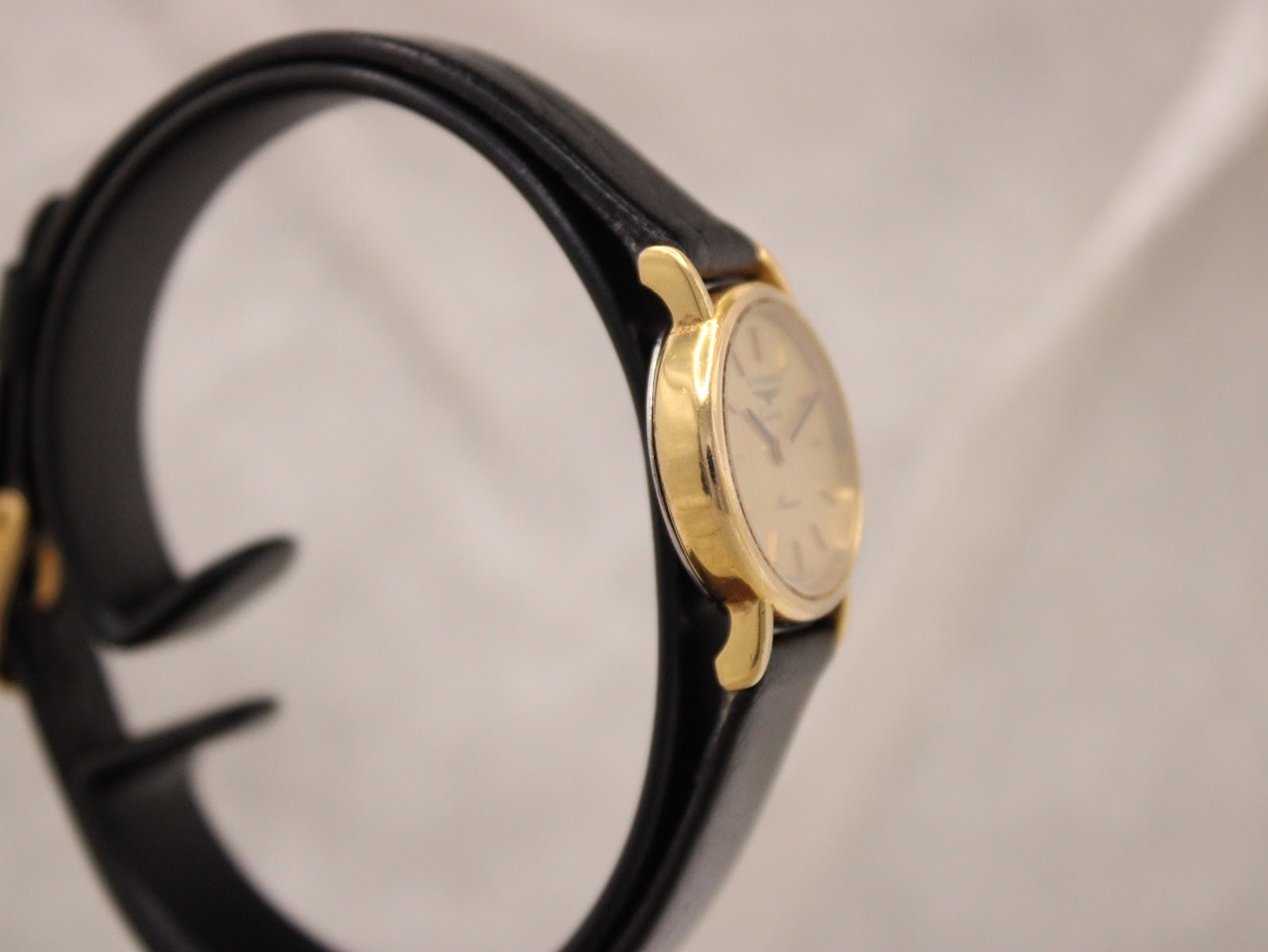 Left-side profile view of the Longines Présence watch on a display stand, showcasing the slim gold-tone case.