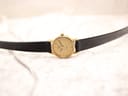 Top-down view of the Longines Présence watch lying flat, displaying the black leather strap and gold-tone case.