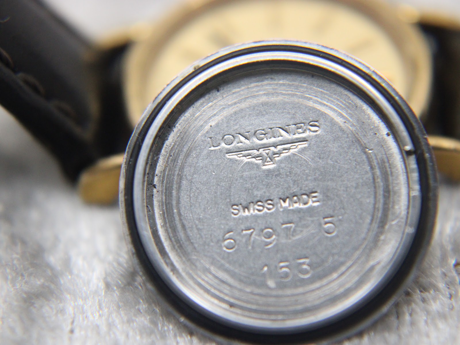 Close-up view of the inside of the watch case back, showing "LONGINES", the winged hourglass logo, "SWISS MADE", and reference numbers "6797 5" and "153".