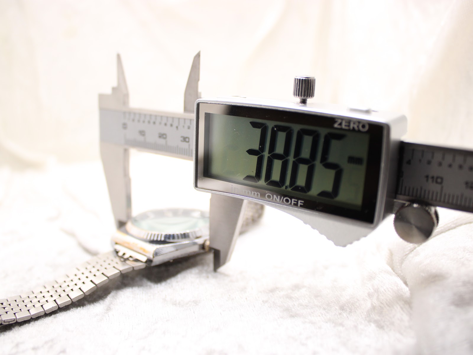 Digital caliper measuring the watch case width, displaying 38.85 mm.