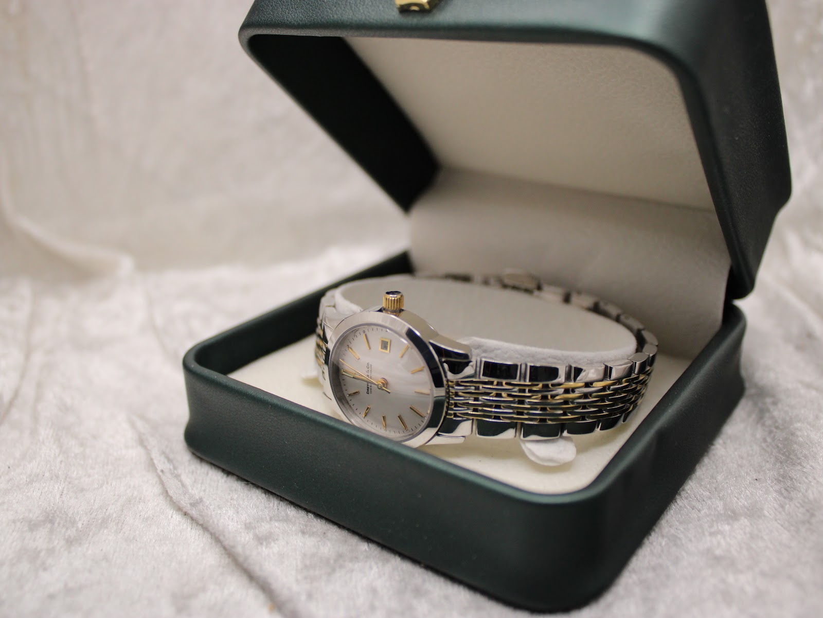 The Dreyfuss & Co watch nestled inside an open green presentation box, resting on a soft white surface.