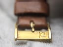 Macro close-up of the gold-tone buckle on the light brown leather strap, featuring the distinct Roamer 'R' logo.