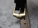 Detailed close-up of the gold-tone buckle on the black leather strap, featuring the distinct Rotary wing logo engraving.