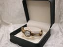 Michel Herbelin watch presented inside an open dark green presentation box on a white textured surface.
