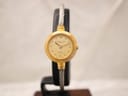 Front view of the Favre-Leuba watch on a stand, showing the gold-tone case, gold dial, and two-tone cable bracelet.