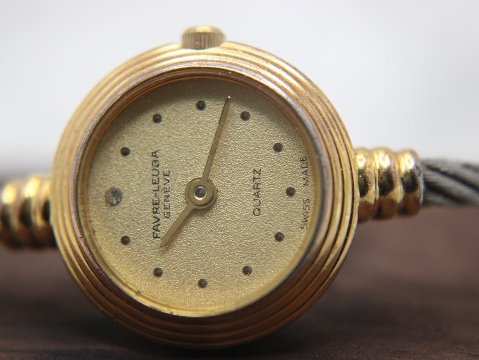 Close-up of the watch dial, showing "FAVRE-LEUBA GENEVE", "QUARTZ", "SWISS MADE", minimalist dot markers, and gold-tone hands.