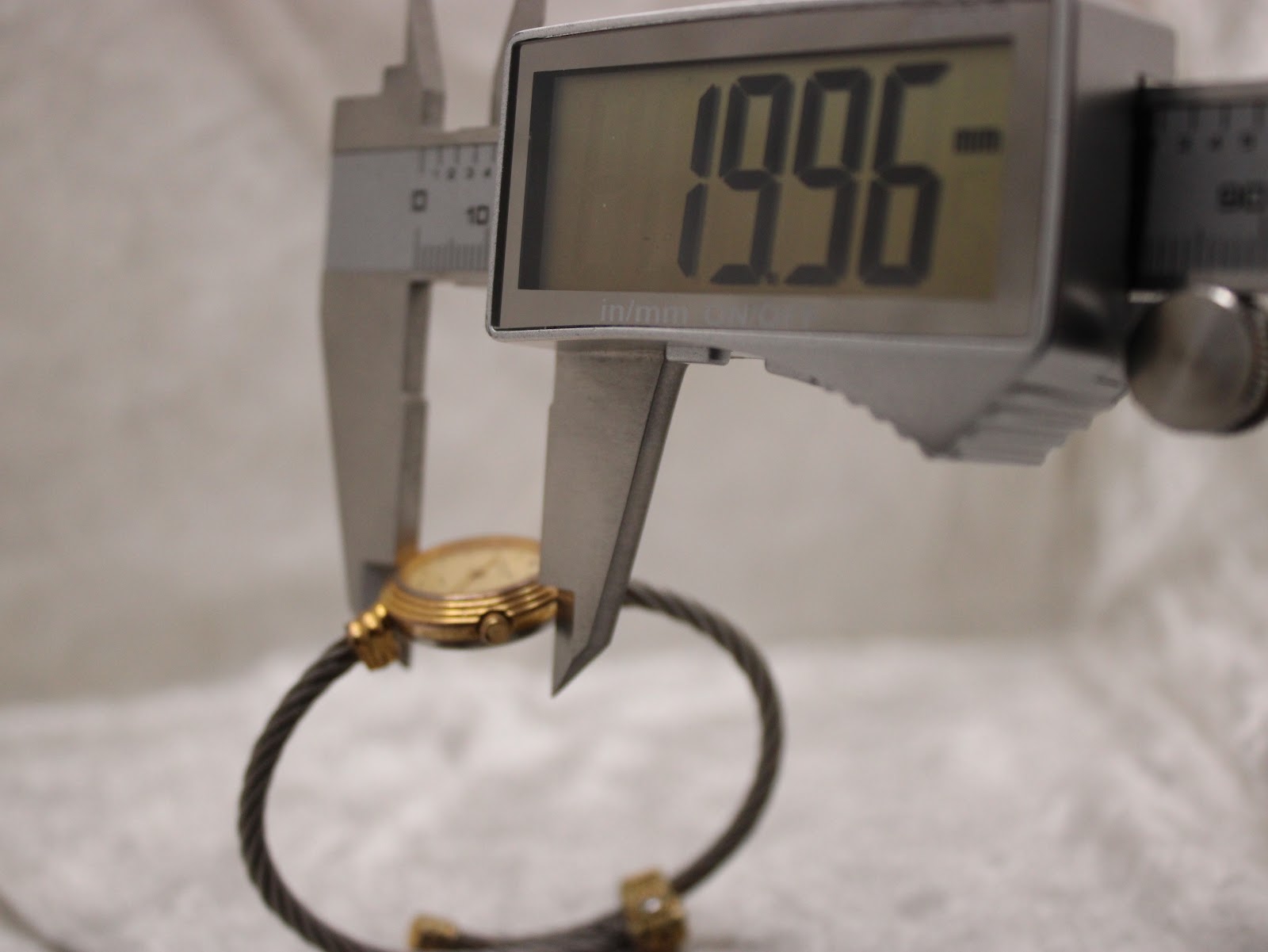 Digital caliper measuring the watch case diameter, showing a precise reading of 19.96mm.