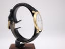 Another side profile view of the watch on a stand, showcasing the gold case and the texture of the black leather strap.