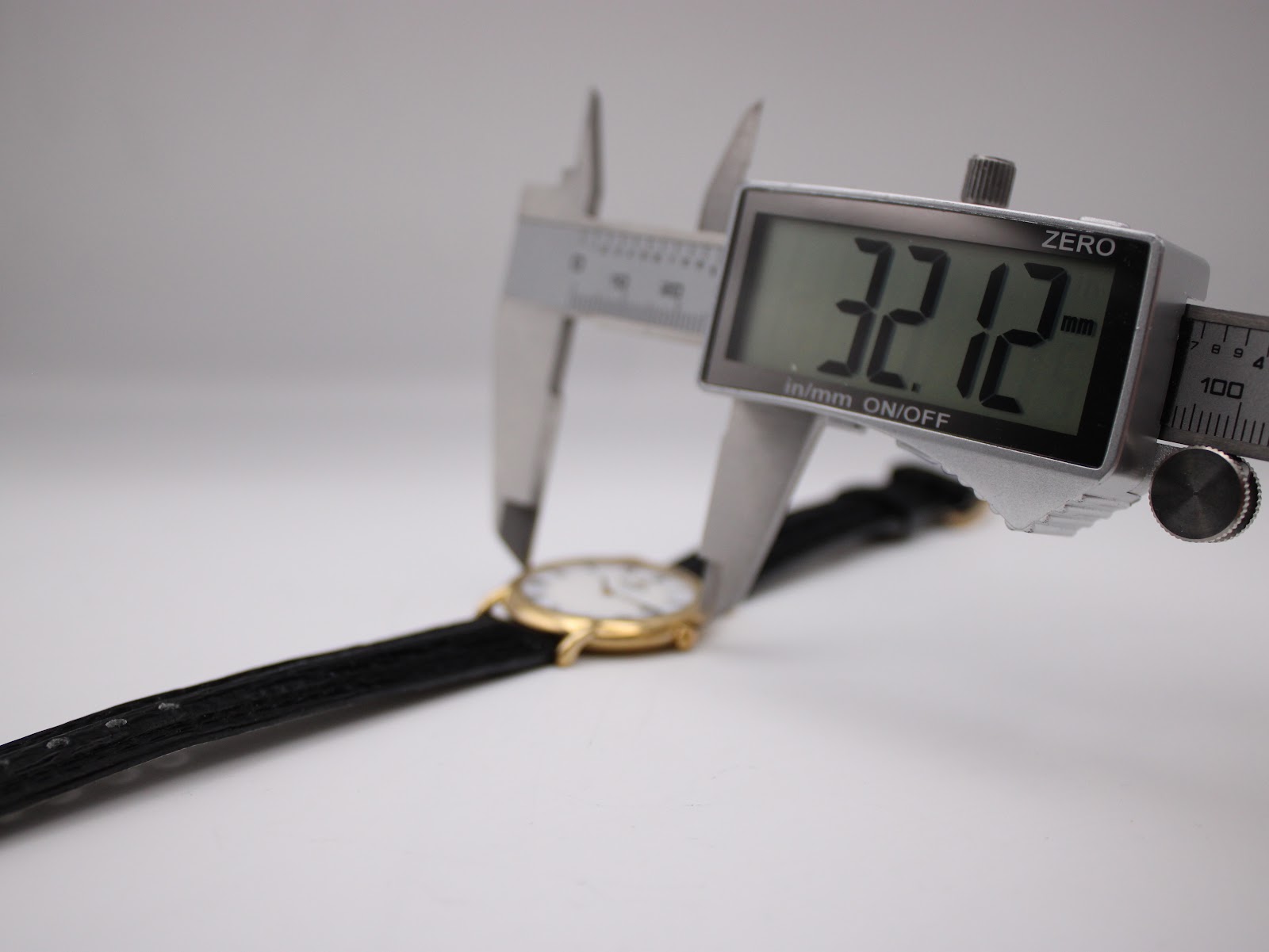 Digital caliper measuring the watch case, displaying a precise diameter of 32.12 mm.