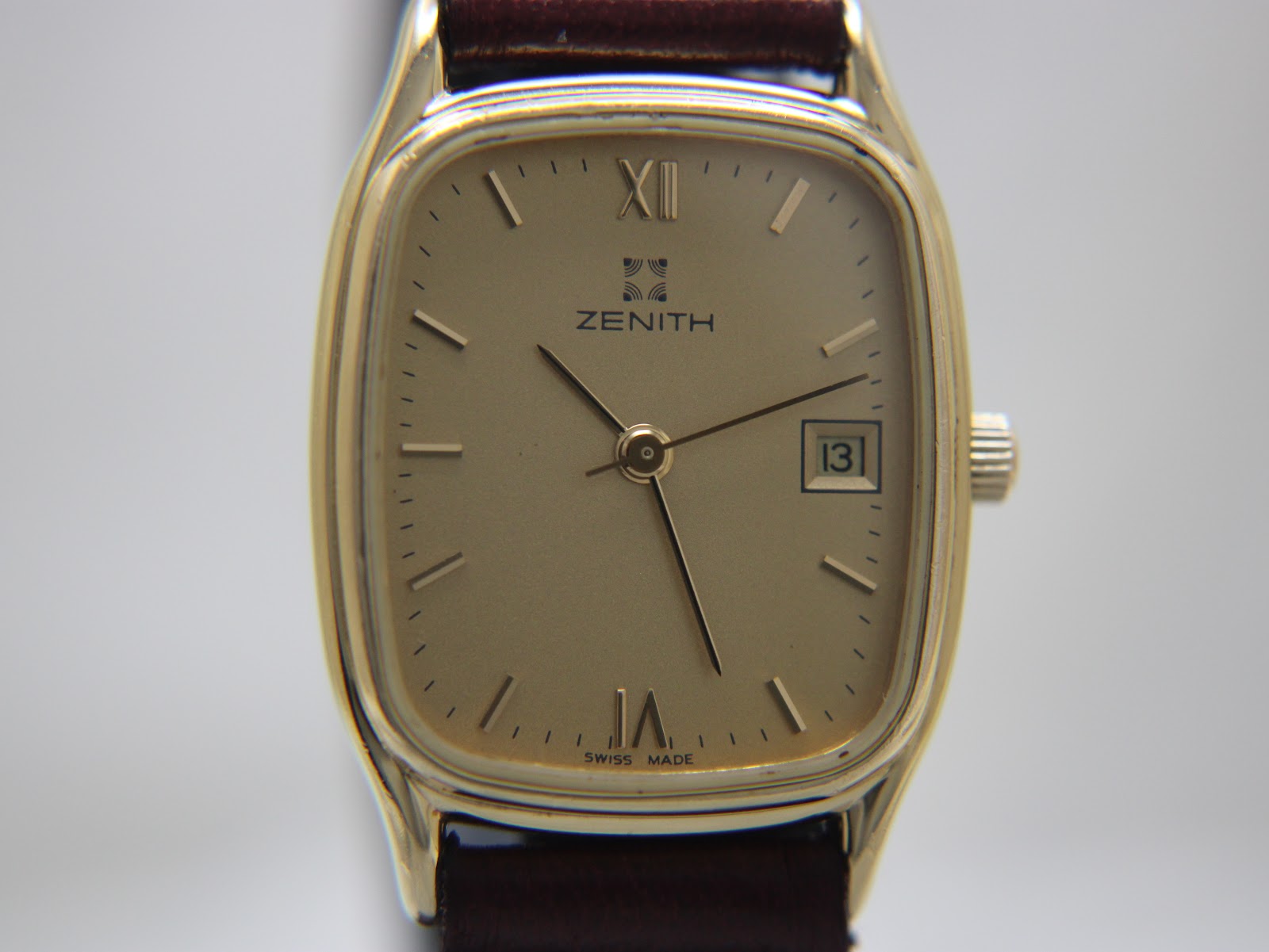 Front view close-up of the Zenith gold-plated rectangular dial with applied indices, roman numerals, and date window.