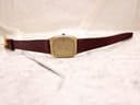 Zenith watch with burgundy leather strap laid flat on a textured white surface.