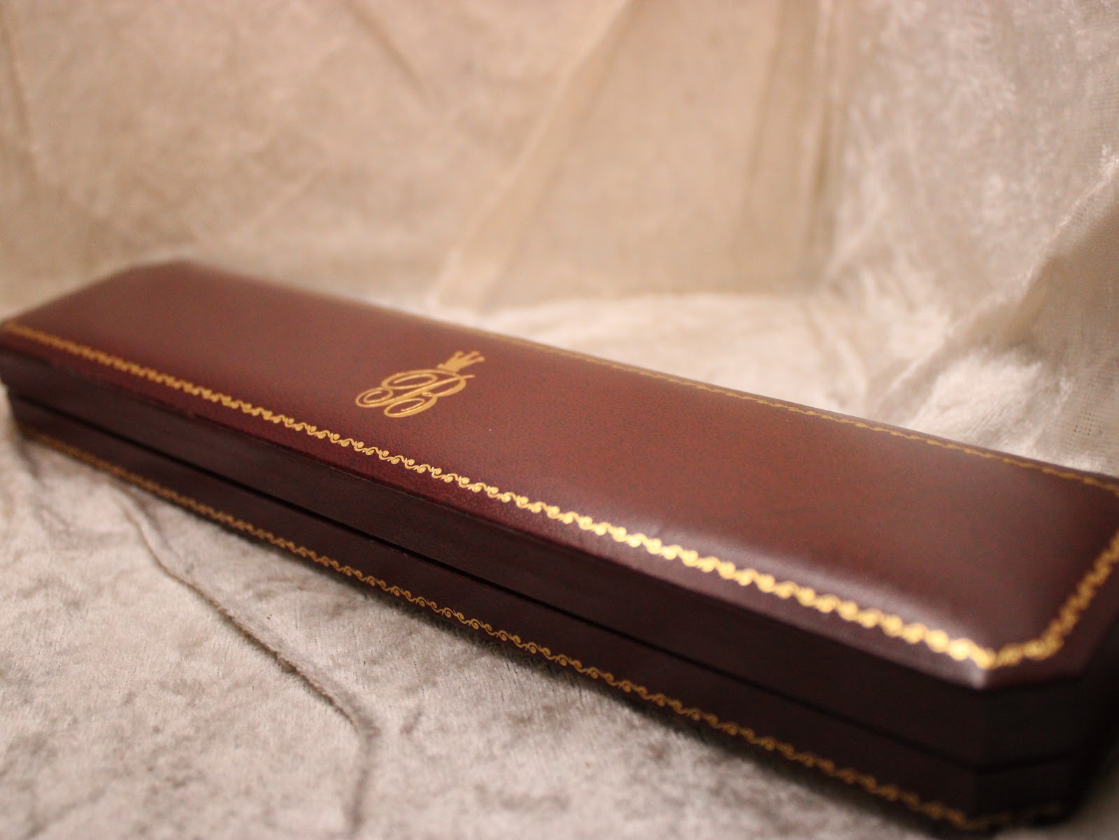 Closed brown display box with gold trim and F.H. Buck Jewellers logo.