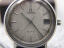 Close-up of the silver linen textured dial of the Omega De Ville, showing the Omega logo, "AUTOMATIC" and "DE VILLE" text, and the framed date window.