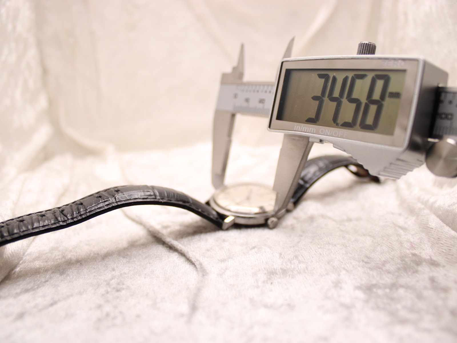 Digital caliper displaying a measurement of 34.58mm across the watch case, indicating its diameter.
