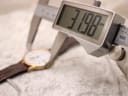 A digital caliper measuring the watch case, with the display showing a precise diameter of 31.98mm.