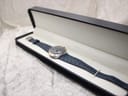 The Omega Genève Dynamic watch resting inside a black presentation box, showing the blue dial and strap.
