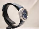Another side profile view of the Omega Genève Dynamic watch, highlighting the brushed finish of the oval stainless steel monobloc case.