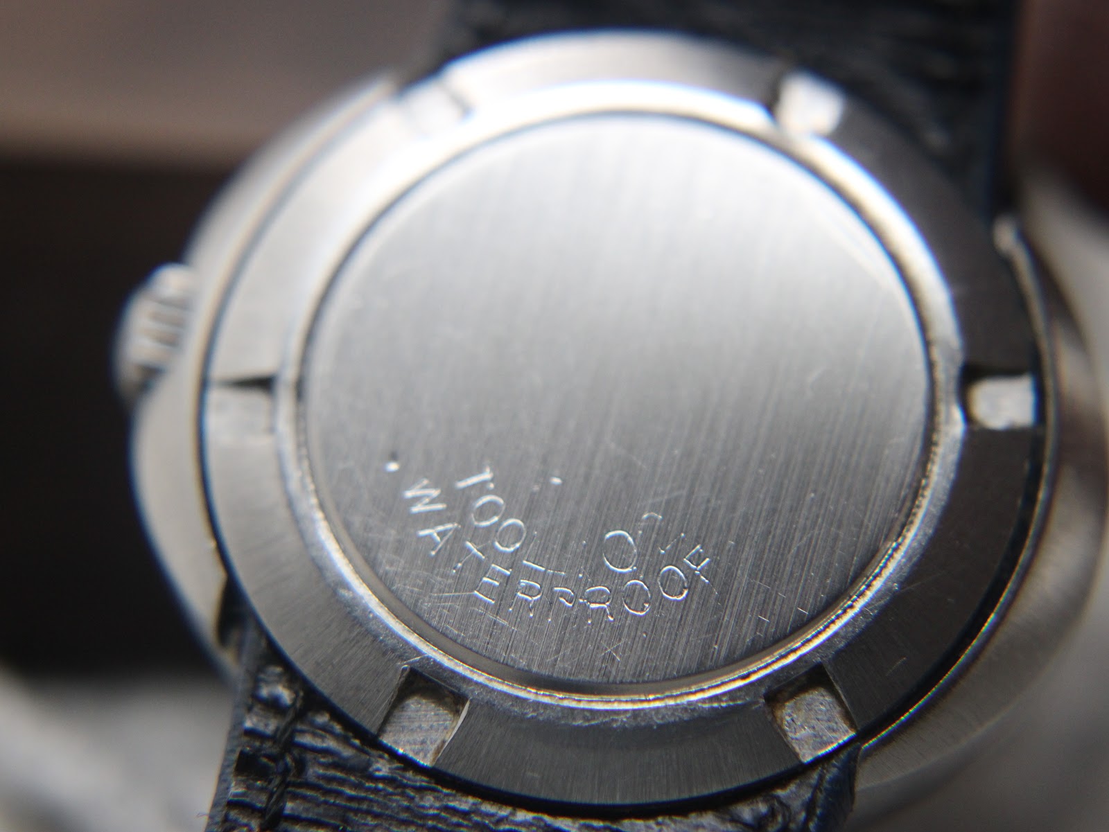 Close-up of the brushed stainless steel case back of the Omega Genève Dynamic, showing the tool markings and "WATERPROOF" text.