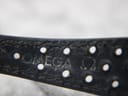 Close-up of the blue perforated leather strap, showing the embossed "OMEGA" logo and strap holes.