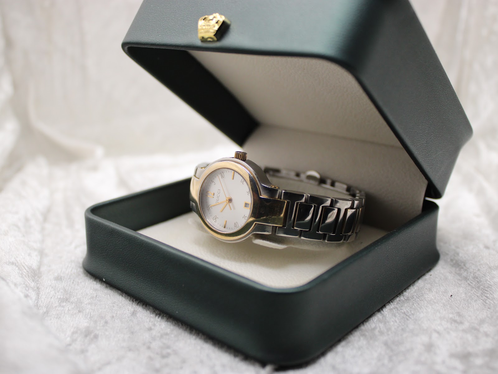 The Gucci 8900L bi-tone watch displayed in a dark green presentation box, highlighting its elegant appearance.