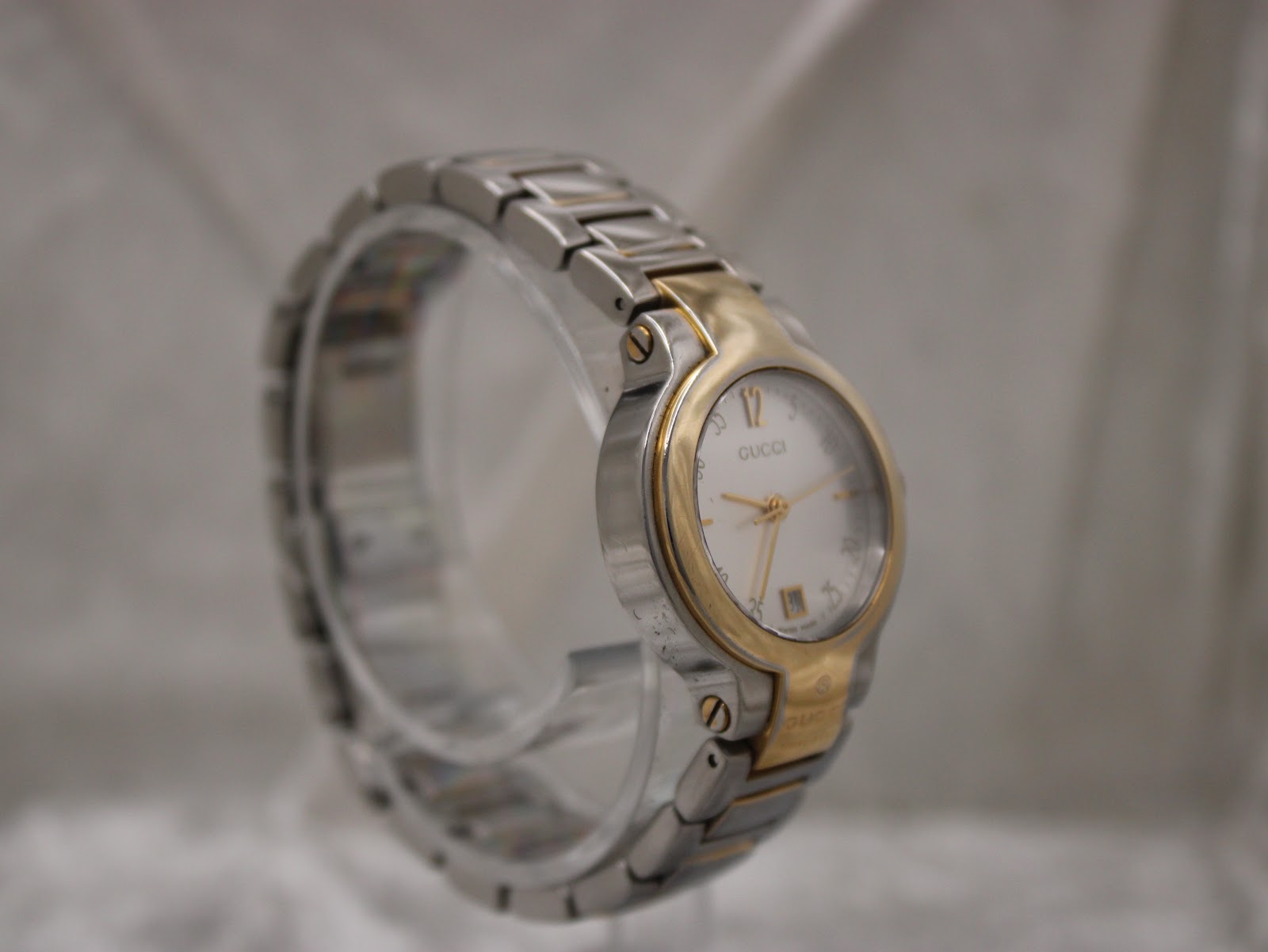 Another angled view of the Gucci 8900L timepiece, showcasing its round case and integrated two-tone bracelet design.