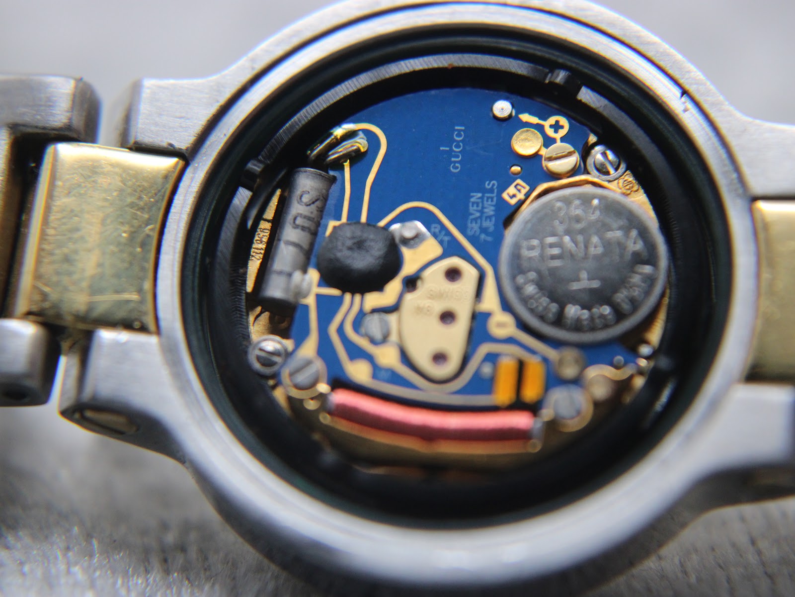 Detailed internal view of the Swiss quartz movement, showing the 7 jewels, "Gucci" marking, and a Renate battery.
