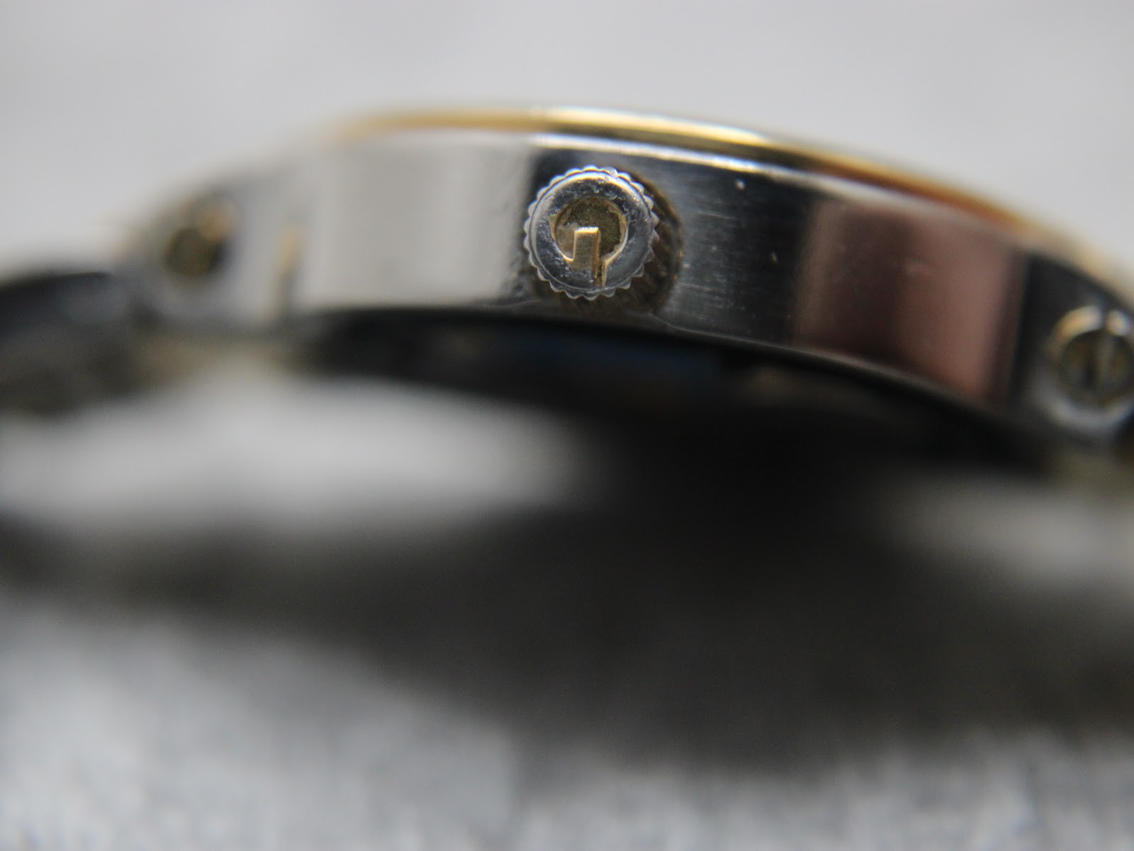 Macro shot of the original gold-tone Gucci signed crown, featuring the iconic 'G' logo.