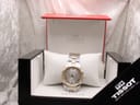 The Tissot PR 100 watch resting on a pillow inside its original Tissot presentation box with booklets.