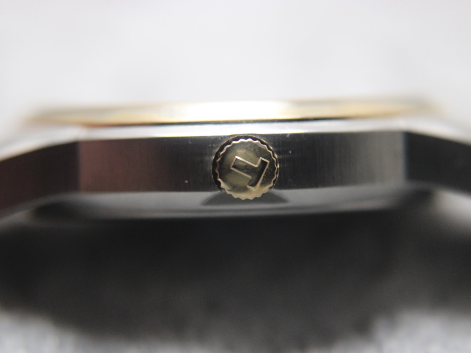 Macro close-up of the gold-tone Tissot signed crown with the 'T' logo.