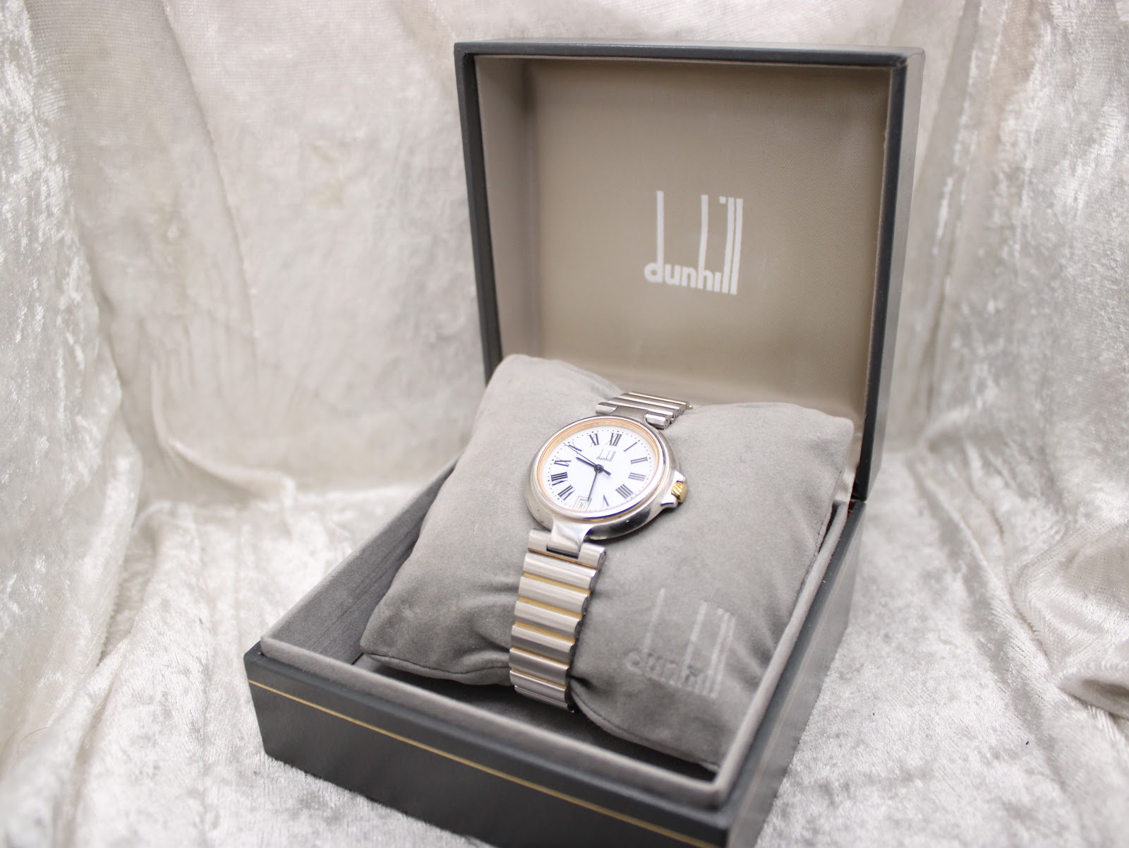 Overhead view of the Dunhill watch in its open presentation box, showing the Dunhill logo.