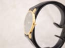 Side profile of the Movado Museum watch, highlighting its thin gold-plated case and crown on a watch stand.