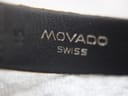 Close-up of 'Movado Swiss' branding embossed on the black textured leather strap.
