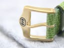 Close-up of the gold-tone buckle of the Gucci watch, featuring the engraved interlocked Gs Gucci logo.