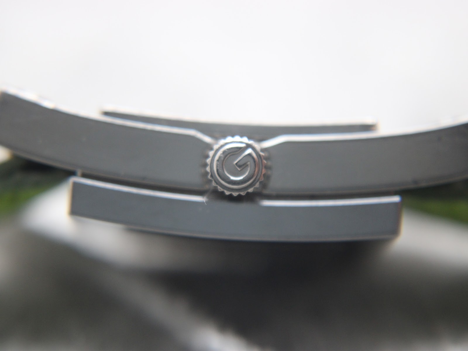 Extreme close-up of the watch crown, showing the ridged texture and the subtle engraved Gucci G logo.