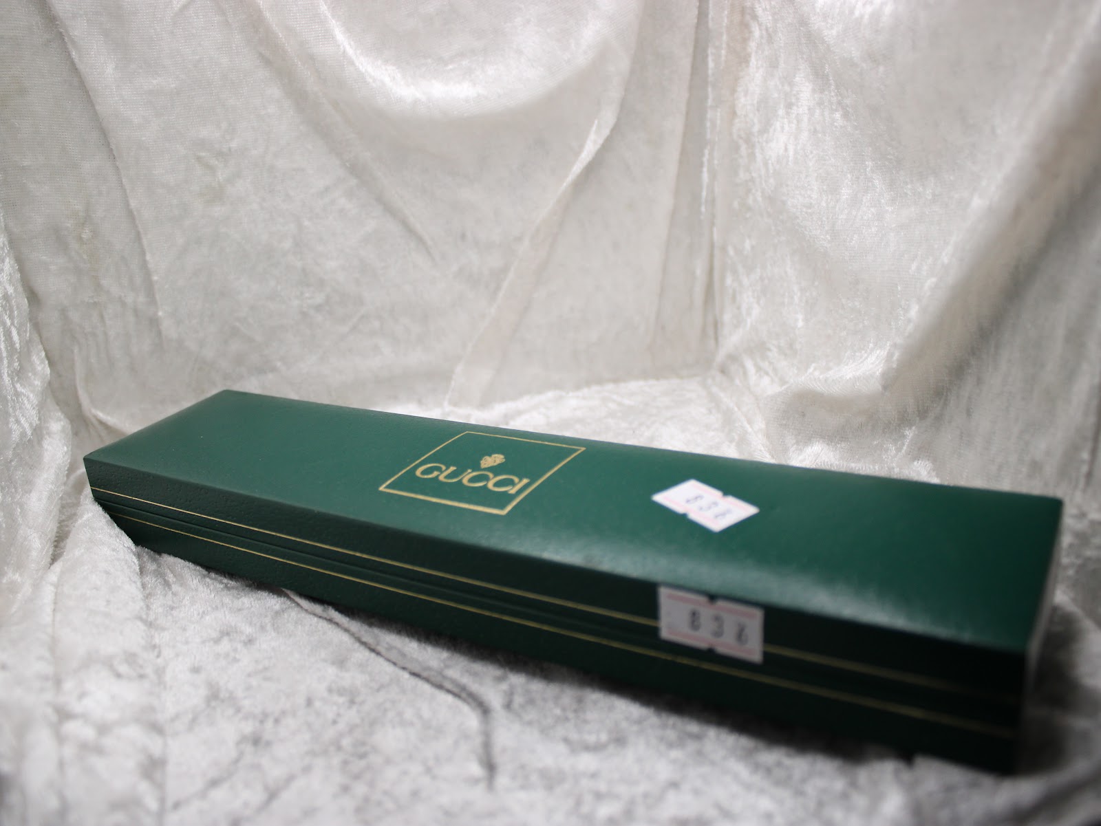 Closed, original dark green Gucci presentation box with golden logo, featuring a small white label with "836".