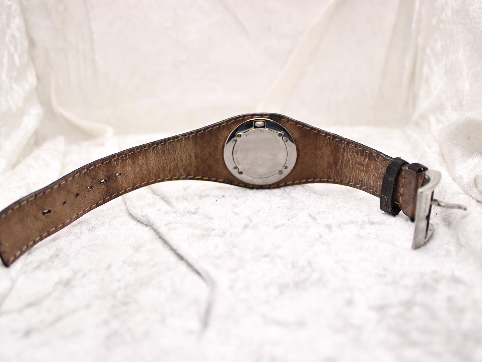 Back view of the Gucci 104 watch with the dark brown leather strap laid flat, showing the stainless steel case back.