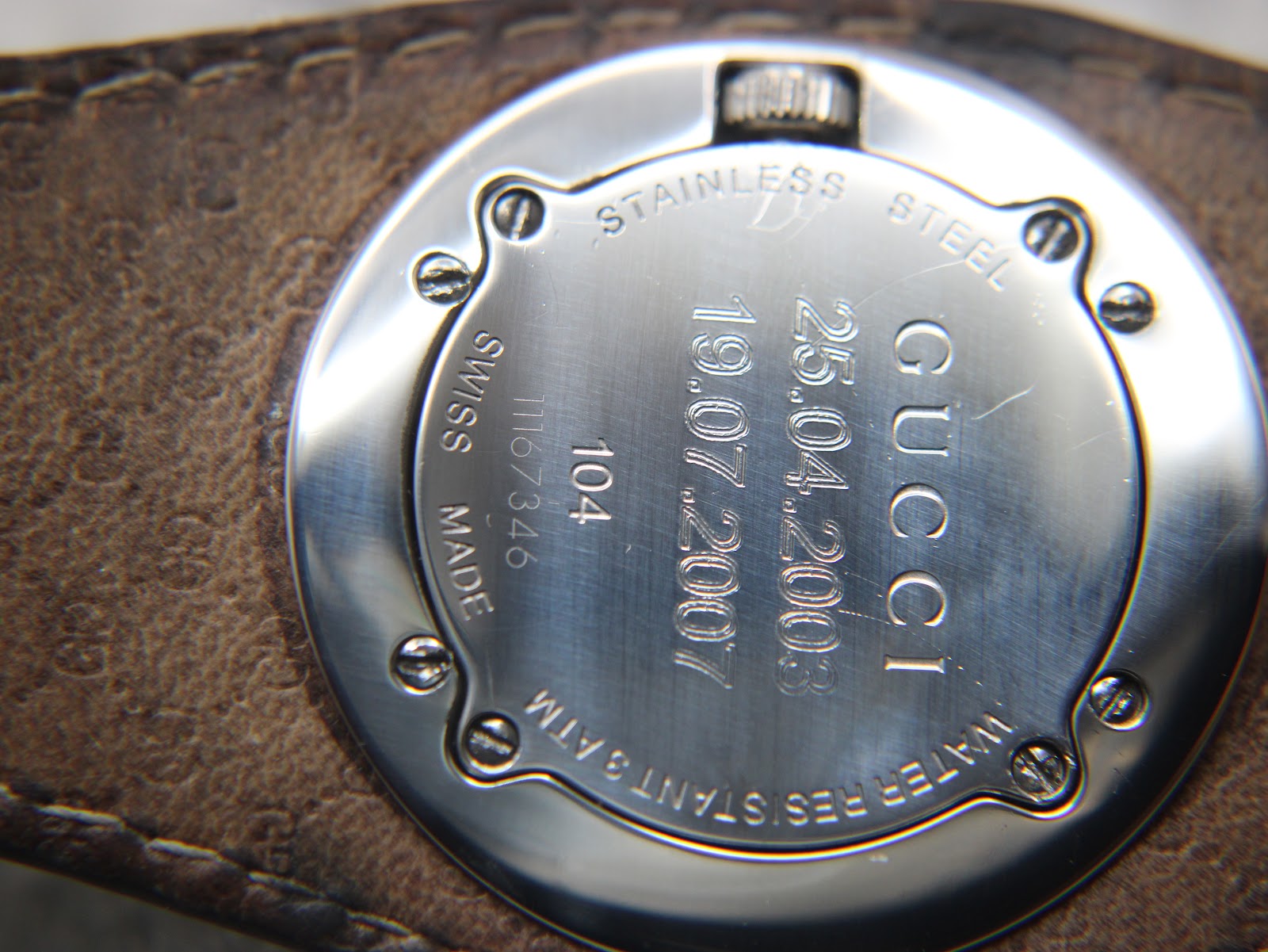 Close-up of the Gucci 104 stainless steel case back, engraved with "Gucci", "Swiss Made", "104", "1167346", "Water Resistant 3ATM", and two personal dates.