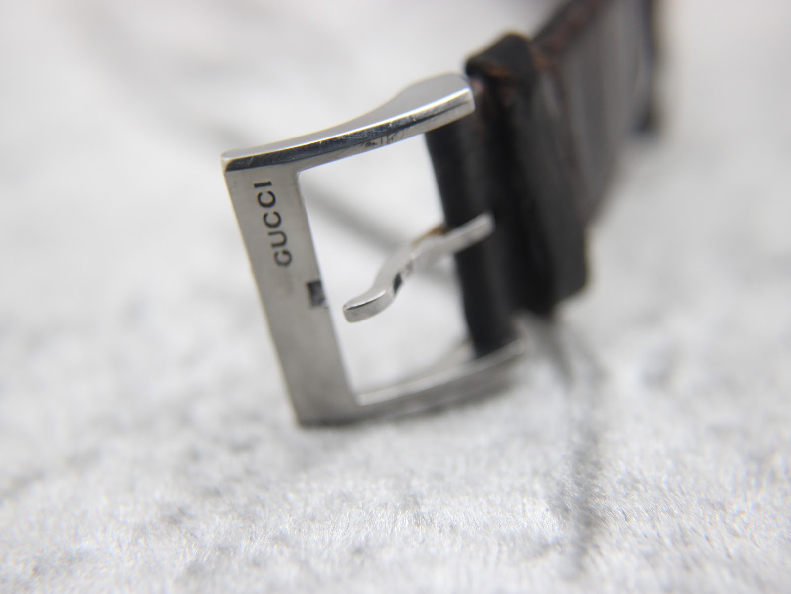 Close-up of the stainless steel buckle, clearly showing the "GUCCI" engraving.