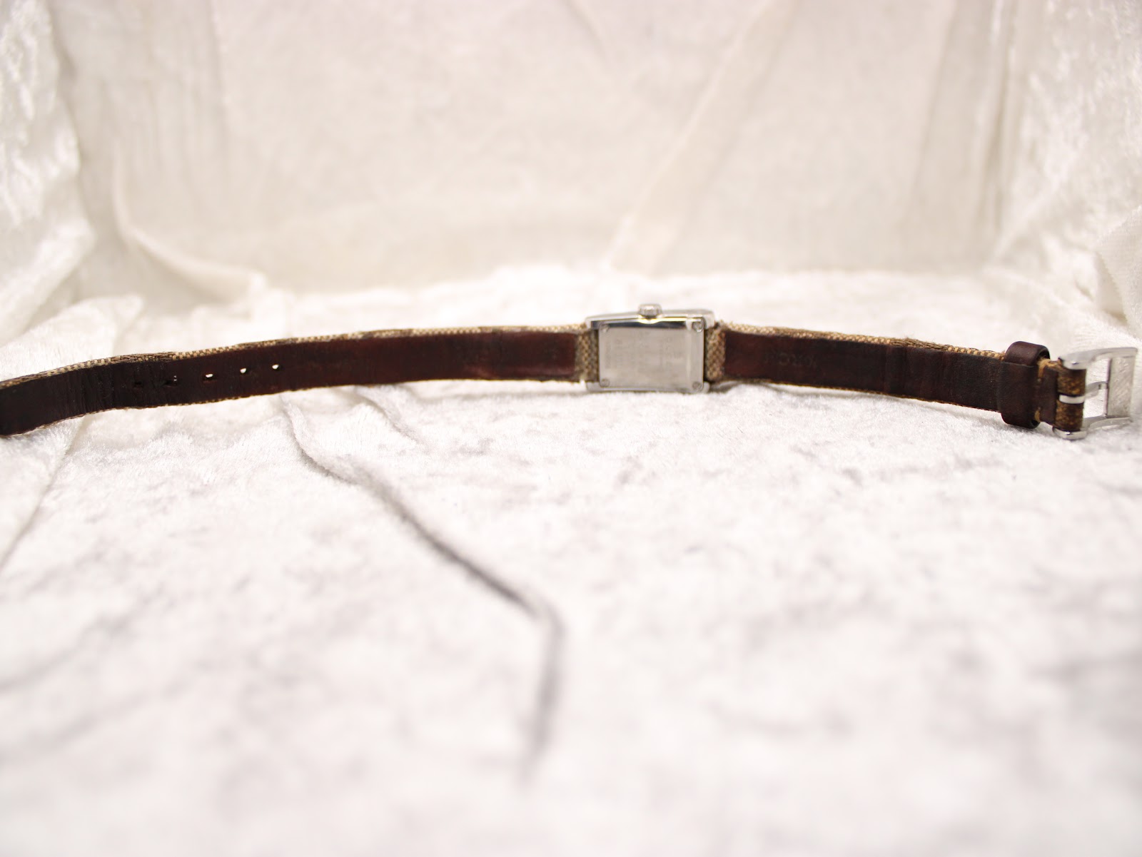 Back view of the Gucci 8600L watch with the fabric strap laid flat, revealing the underside of the strap and case back.