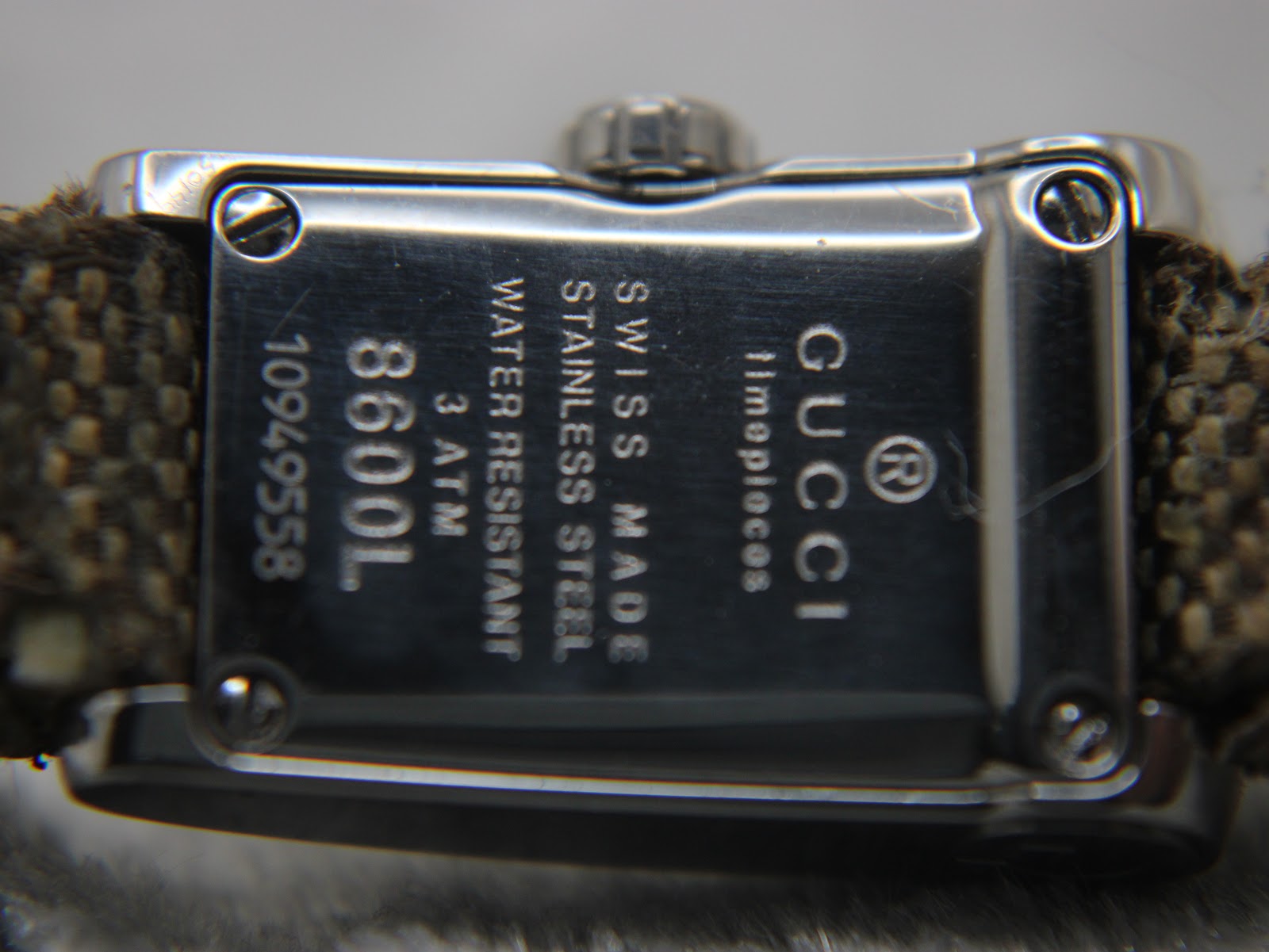 Close-up view of the Gucci 8600L stainless steel case back, showing engravings for "Swiss Made", "Water Resistant 3 ATM", "8600L", and serial number.