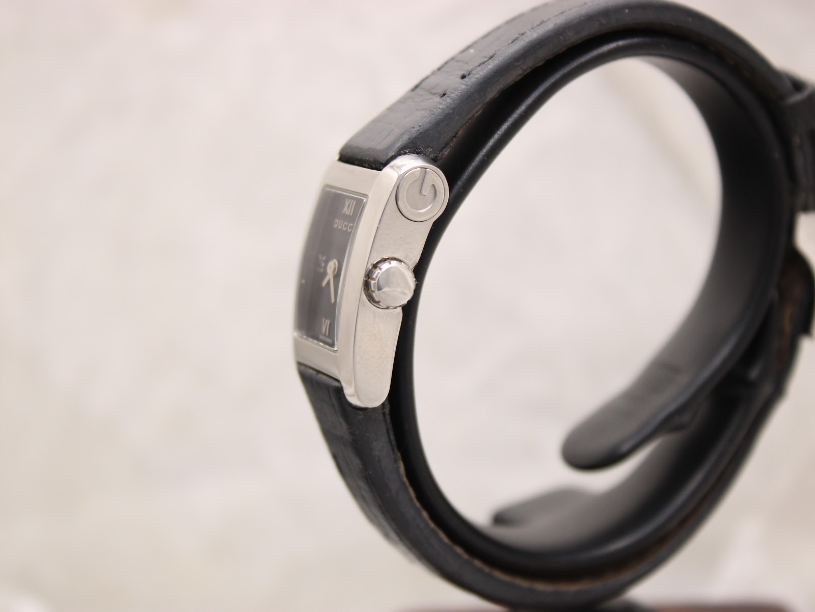 Angled side view of the Gucci 8600L watch, showcasing the rectangular stainless steel case and the crown with Gucci logo.