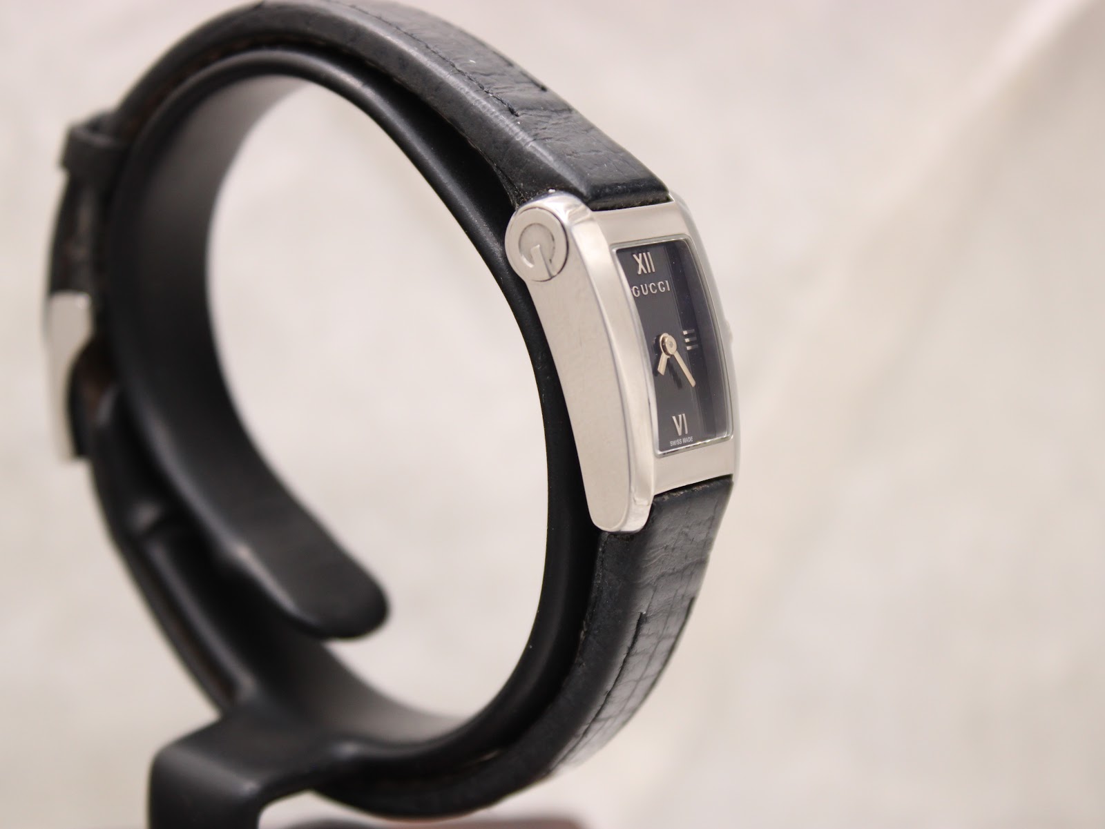 Another angled side view of the Gucci 8600L watch on a display stand, highlighting its slim profile and design.