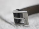 Close-up of the polished stainless steel pin buckle, with the "GUCCI" name engraved on its side.